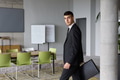 A determined businessman in a black suit confidently walks through the office, embodying - PhotoDune Item for Sale