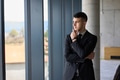 A close up portrait of a company director in a black suit, standing confidently in a modern office - PhotoDune Item for Sale