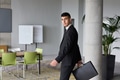 A determined businessman in a black suit confidently walks through the office, embodying - PhotoDune Item for Sale