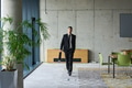 A determined businessman in a black suit confidently walks through the office, embodying - PhotoDune Item for Sale