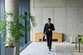 A determined businessman in a black suit confidently walks through the office, embodying - PhotoDune Item for Sale