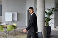 A determined businessman in a black suit confidently walks through the office, embodying - PhotoDune Item for Sale