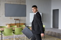 A determined businessman in a black suit confidently walks through the office, embodying - PhotoDune Item for Sale