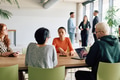 A diverse team of business professionals engaged in a discussion around a conference table in an - PhotoDune Item for Sale