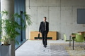 A determined businessman in a black suit confidently walks through the office, embodying - PhotoDune Item for Sale