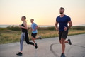 A diverse group of runners trains together at sunset. - PhotoDune Item for Sale